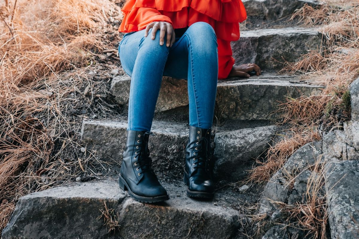 Denim leg warmers styled over blue jeans with black lace-up boots on stone steps