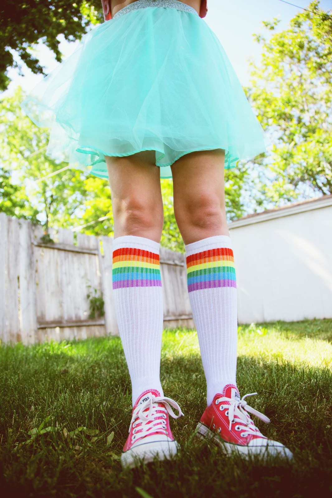 Over the knee socks in rainbow stripes styled with a tulle skirt and trainers
